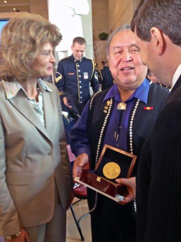 Ozzie Sheakley holds the Congressional Gold Medal While Speaking to Senators Lisa Murkowski and Mark Begich