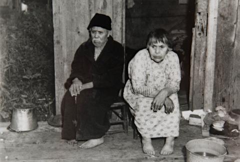 An Elder Man and Woman Sit in Front of Temporary Housing Post Fire