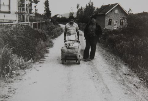Two Men Walking Down the Street with a Cart of Supplies